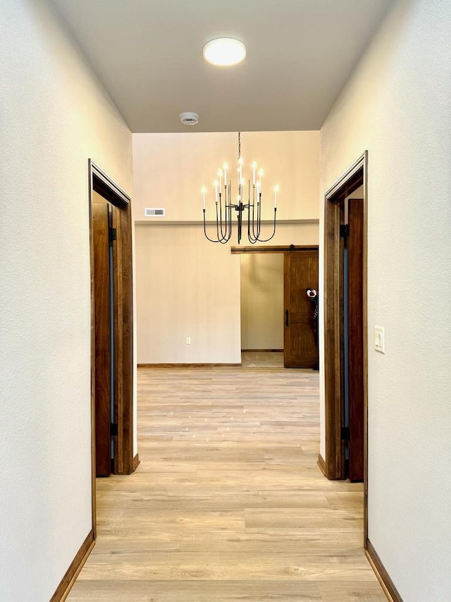 hallway featuring an inviting chandelier and light hardwood / wood-style flooring