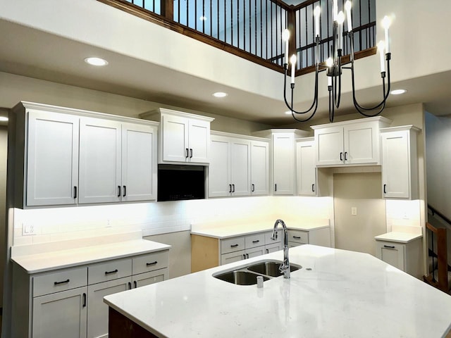 kitchen featuring white cabinetry, sink, a kitchen island with sink, and decorative light fixtures