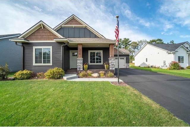 craftsman house featuring a garage, covered porch, and a front lawn