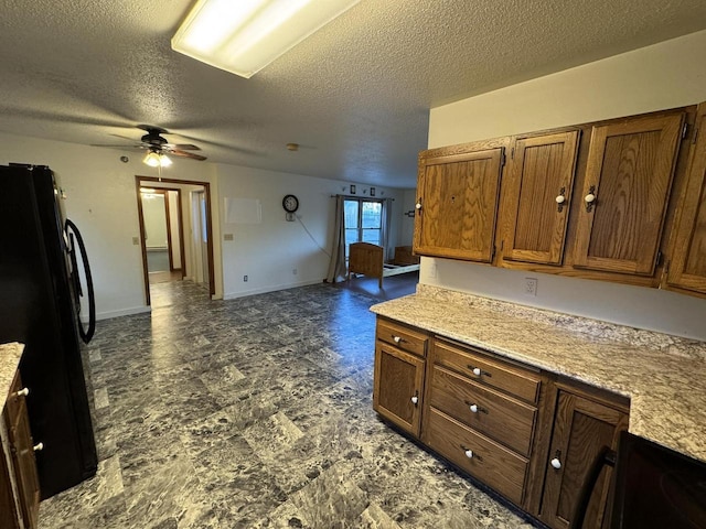 kitchen featuring black fridge, ceiling fan, and a textured ceiling