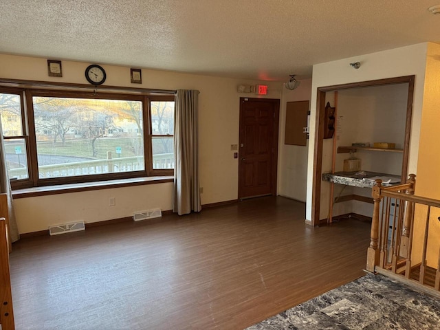 empty room with dark hardwood / wood-style floors and a textured ceiling