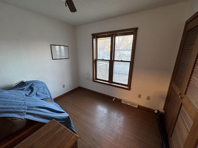 unfurnished bedroom featuring dark wood-type flooring, a textured ceiling, and ceiling fan