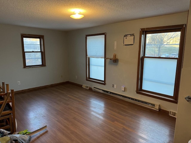 empty room with baseboard heating, dark hardwood / wood-style floors, and a textured ceiling