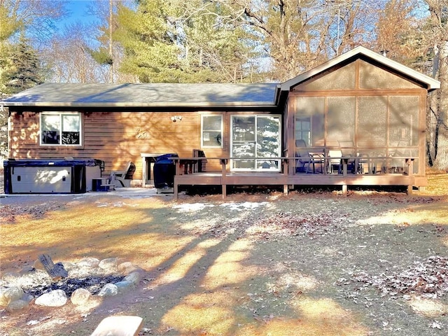 back of house with a sunroom, a wooden deck, and a hot tub