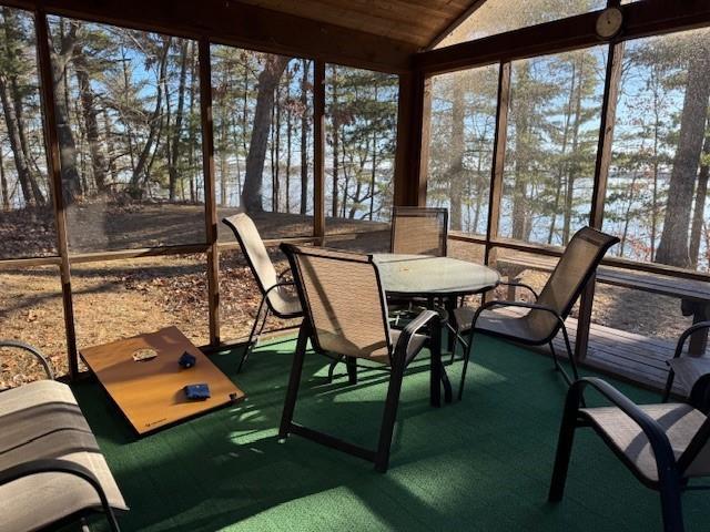 sunroom with plenty of natural light, a water view, lofted ceiling, and wooden ceiling