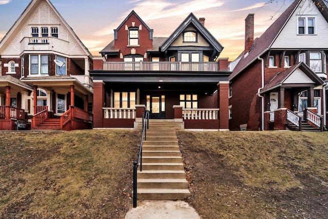 view of front of property featuring a yard, a balcony, and a porch