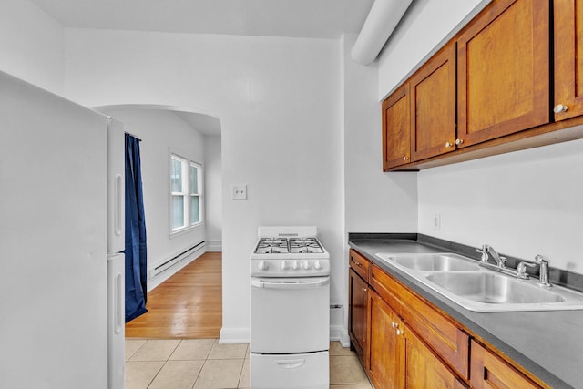 kitchen featuring sink, light tile patterned floors, white appliances, and a baseboard heating unit