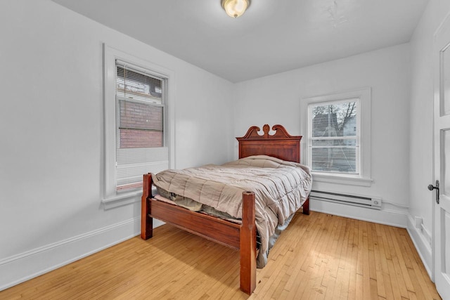 bedroom featuring baseboard heating and light hardwood / wood-style flooring