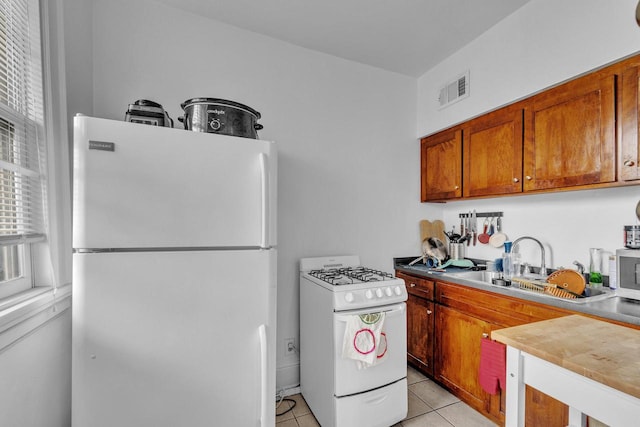 kitchen with sink, light tile patterned floors, and white appliances