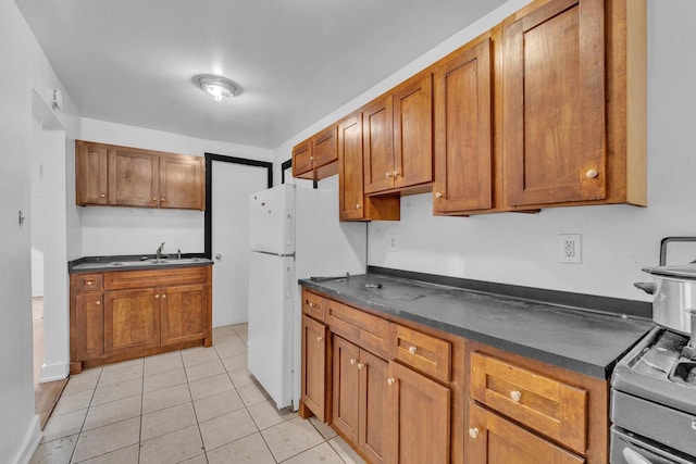 kitchen featuring stainless steel electric range, light tile patterned flooring, white refrigerator, and sink