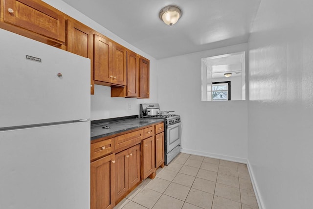 kitchen featuring white refrigerator, range with gas cooktop, and light tile patterned flooring