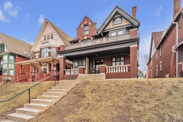 view of front facade with a porch, a balcony, and a front lawn