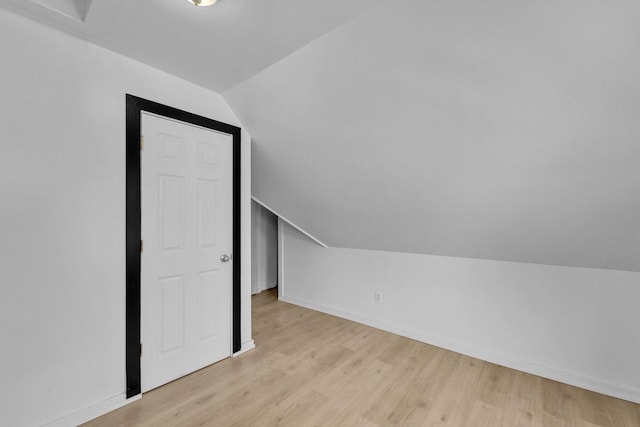 additional living space with light hardwood / wood-style flooring and lofted ceiling