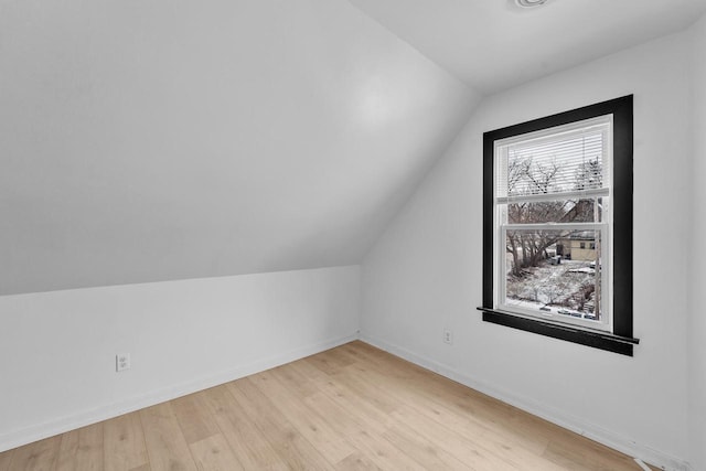 additional living space with light hardwood / wood-style floors and vaulted ceiling