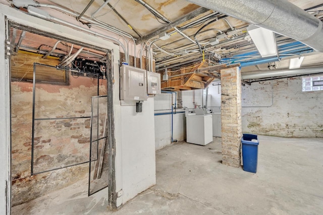 basement with electric panel and washing machine and clothes dryer