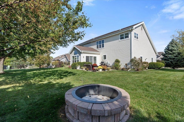 back of house featuring an outdoor fire pit and a lawn