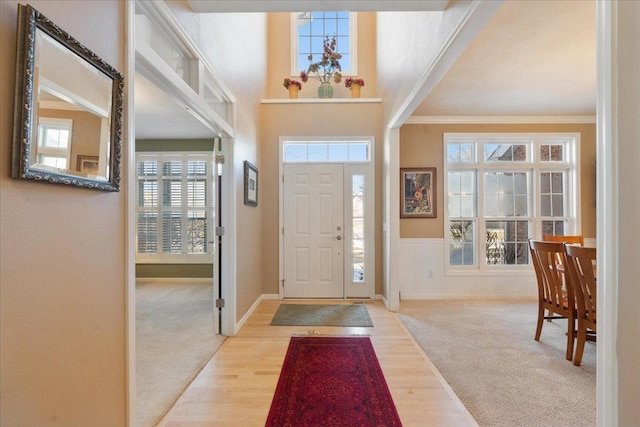 foyer featuring an inviting chandelier, light wood-type flooring, and crown molding