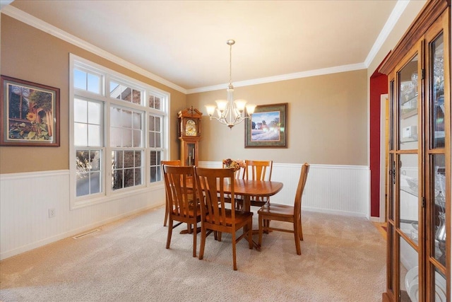 carpeted dining area with a notable chandelier and crown molding