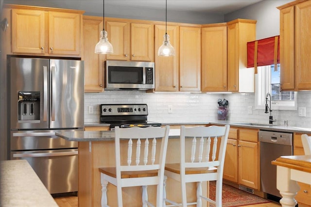 kitchen featuring a kitchen breakfast bar, stainless steel appliances, decorative backsplash, sink, and decorative light fixtures