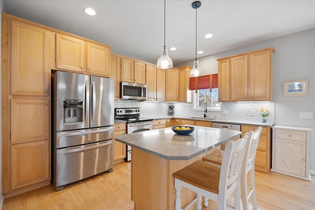 kitchen with sink, decorative light fixtures, backsplash, a kitchen island, and appliances with stainless steel finishes