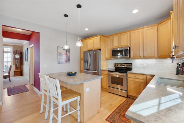 kitchen with light hardwood / wood-style flooring, hanging light fixtures, a center island, appliances with stainless steel finishes, and sink