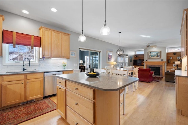 kitchen featuring dishwasher, a kitchen island, a breakfast bar area, ceiling fan, and sink