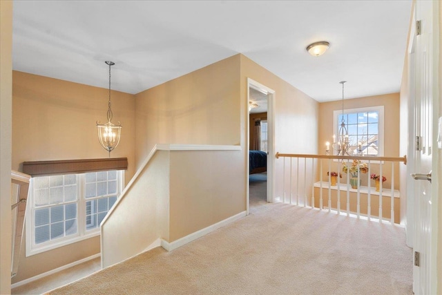 corridor featuring an inviting chandelier and light carpet