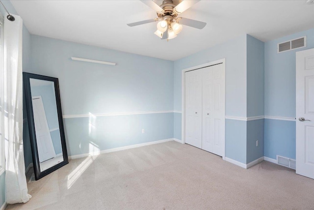 unfurnished bedroom featuring ceiling fan, a closet, and light carpet