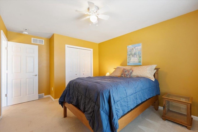 bedroom featuring light colored carpet, ceiling fan, and a closet