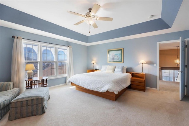 carpeted bedroom with ceiling fan and a tray ceiling