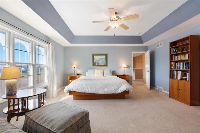 carpeted bedroom featuring a raised ceiling and ceiling fan