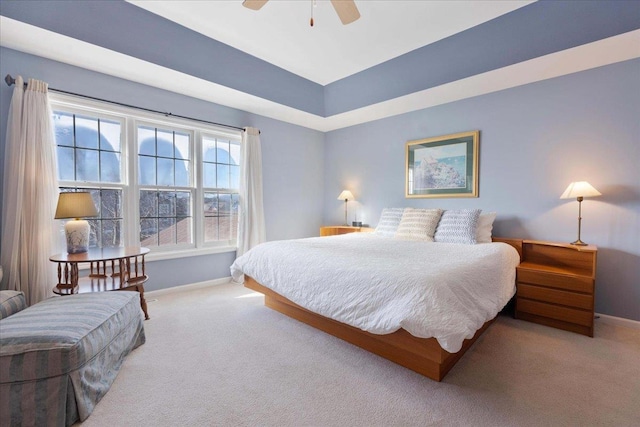 carpeted bedroom featuring ceiling fan and a raised ceiling