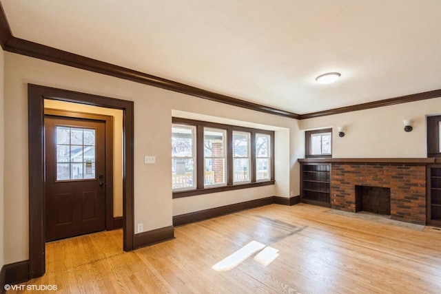 entrance foyer featuring light hardwood / wood-style flooring, a brick fireplace, a wealth of natural light, and ornamental molding