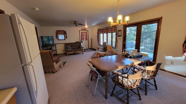 carpeted dining space with ceiling fan with notable chandelier