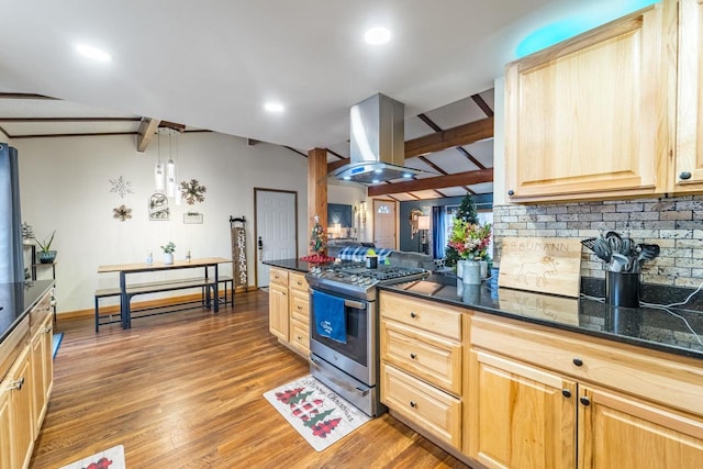 kitchen with stainless steel gas range oven, island range hood, light brown cabinets, and decorative light fixtures