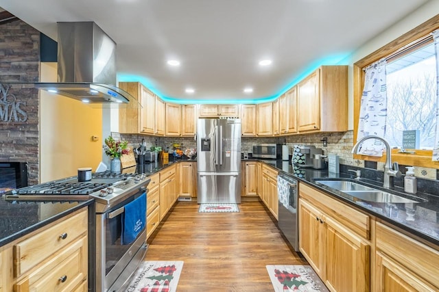 kitchen featuring dark stone counters, stainless steel appliances, wall chimney range hood, and light wood-type flooring