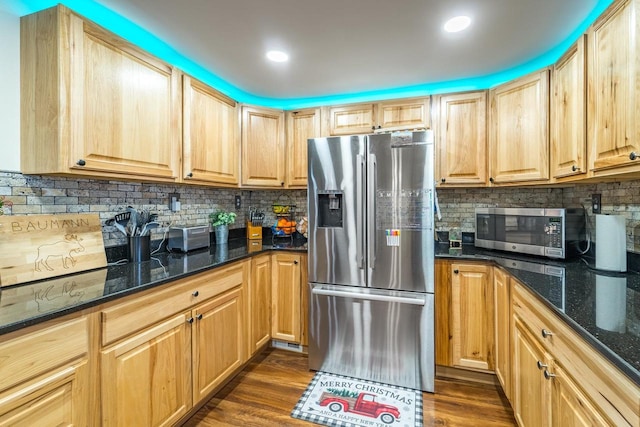 kitchen featuring light brown cabinetry, dark stone countertops, dark hardwood / wood-style flooring, and stainless steel appliances