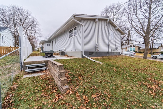 view of side of home featuring central AC unit, a patio area, and a lawn