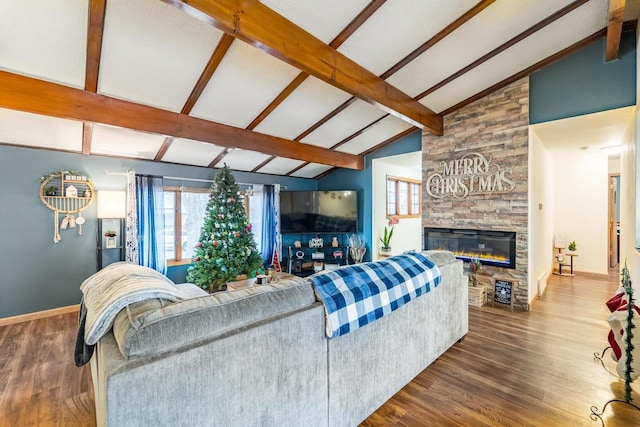 living room featuring hardwood / wood-style floors, lofted ceiling with beams, and a stone fireplace