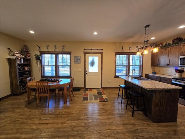 kitchen featuring pendant lighting, backsplash, sink, an island with sink, and appliances with stainless steel finishes