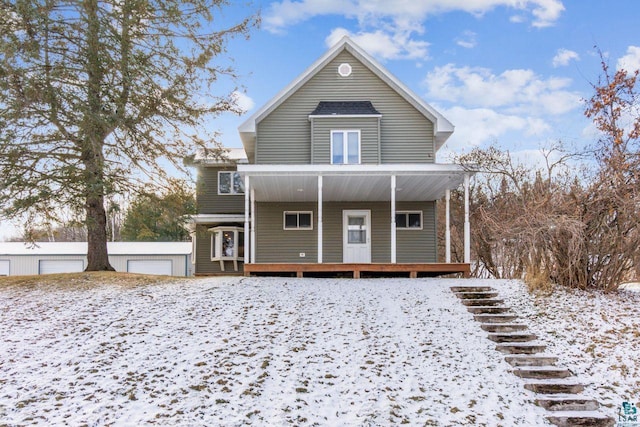 snow covered rear of property featuring a garage and an outdoor structure