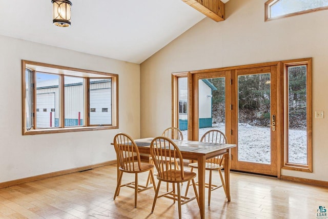 dining space featuring lofted ceiling with beams, a healthy amount of sunlight, and light wood-type flooring