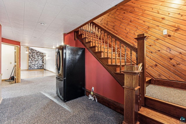 stairway featuring carpet flooring and wood walls