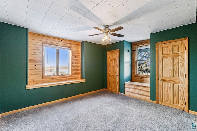 unfurnished bedroom featuring carpet flooring, multiple windows, and ceiling fan