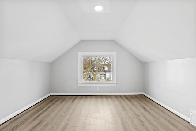 additional living space with light hardwood / wood-style floors and lofted ceiling