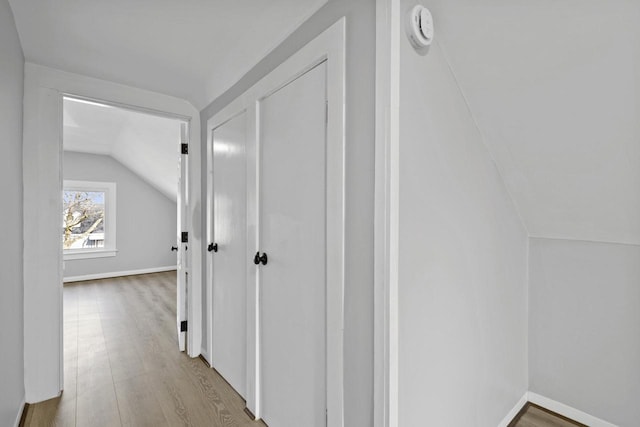 hallway featuring vaulted ceiling and light wood-type flooring