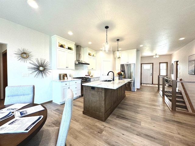 1217 Bay Mist Dr, Green Bay, WI 54311 - kitchen with stainless steel appliances, wall chimney range hood, decorative light fixtures, a kitchen island with sink, and hardwood / wood-style flooring