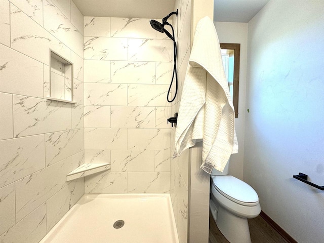 bathroom with hardwood / wood-style flooring, toilet, and tiled shower