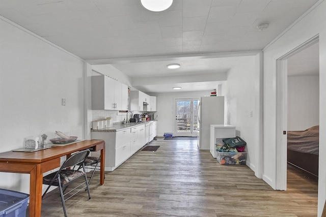 kitchen with backsplash, light hardwood / wood-style floors, sink, white fridge, and white cabinetry