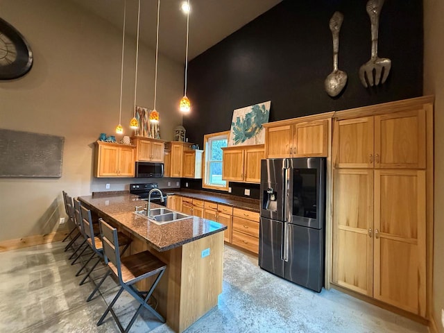 kitchen with pendant lighting, a breakfast bar, sink, stainless steel refrigerator with ice dispenser, and a towering ceiling